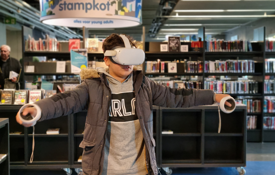 Jongen met VR-bril op en controllers in de handen